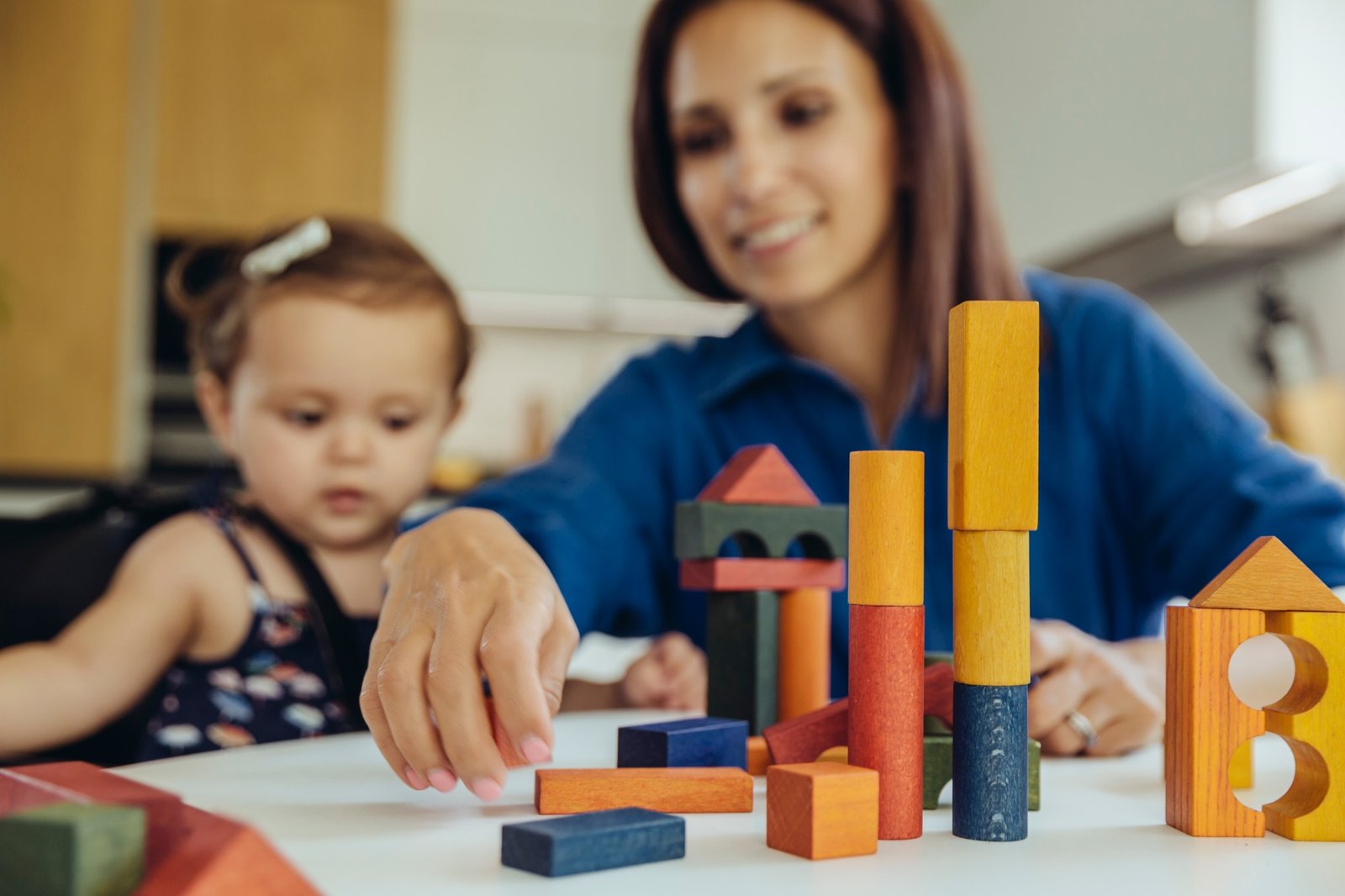 Happy mother and baby daughter playing with building blocks